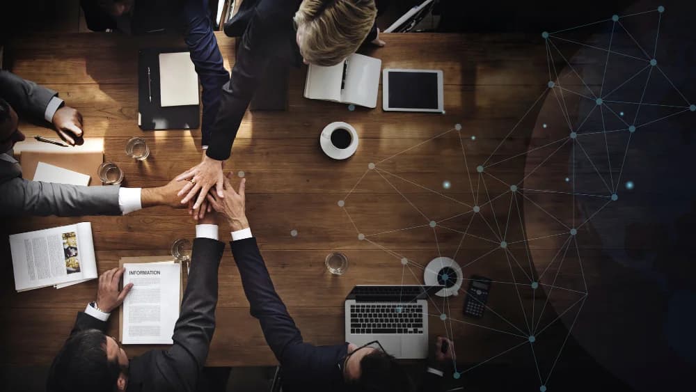Un groupe réunit ses mains autour d’une table de travail