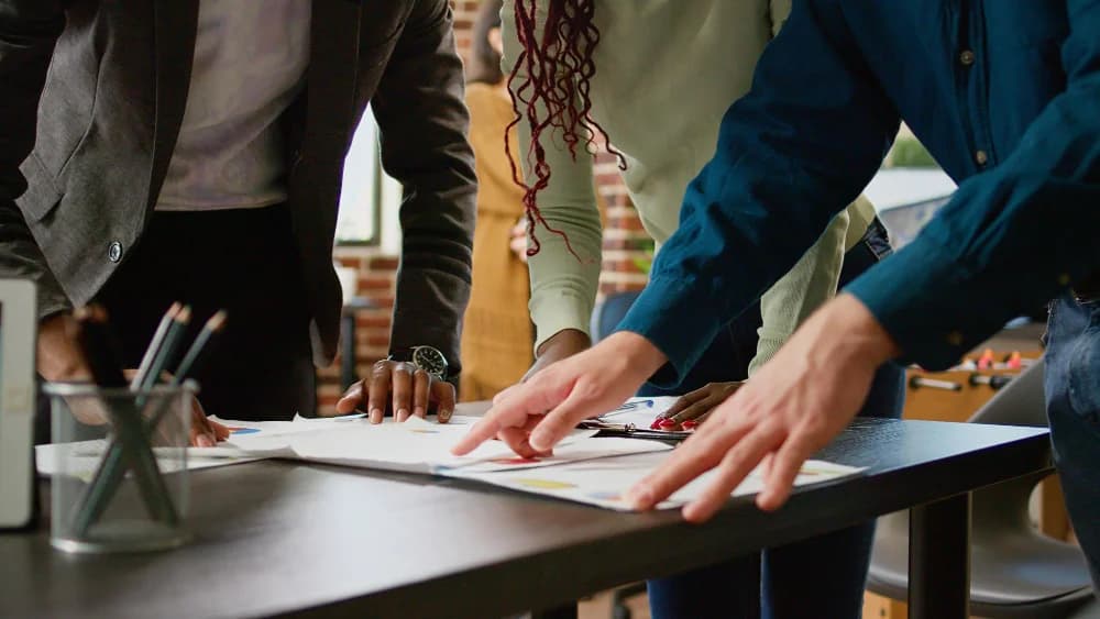 Des collègues qui pointent des documents étalés sur un bureau